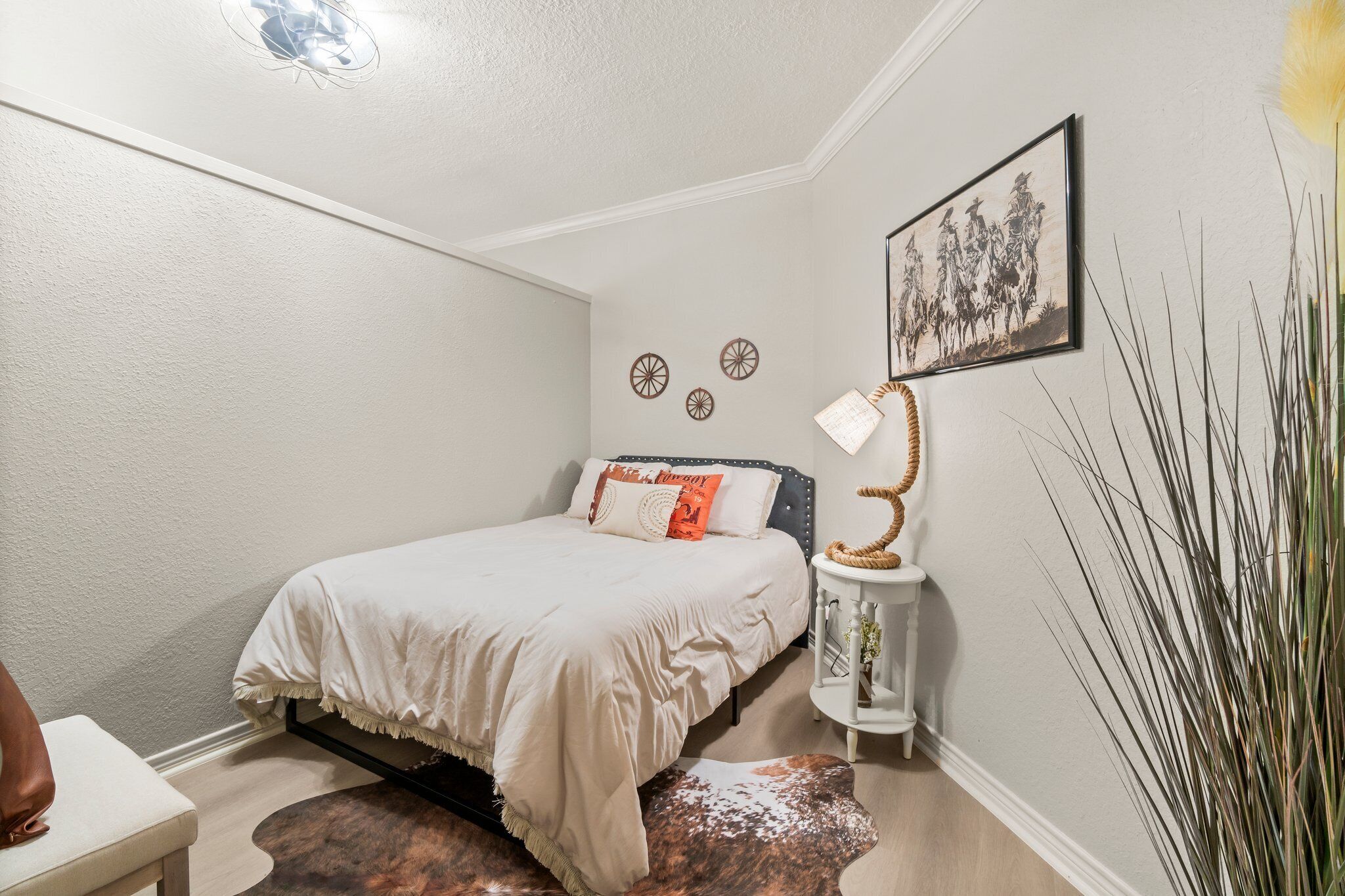 A bedroom with a bed, a bedside table, a lamp, and a wall-mounted picture.
