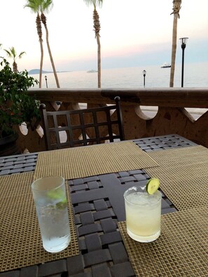 A table with two glasses of beverages, a chair, and a view of the sea with a ship in the distance. - Lovely Three-Bedroom Home in Loreto, Baja Fishing Village (Loreto)