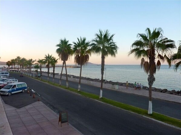 A coastal road lined with palm trees and parked cars, leading to a beach. - Lovely Three-Bedroom Home in Loreto, Baja Fishing Village (Loreto)
