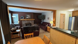 A cozy living room with a fireplace, a television, and a dining area with wooden furniture.