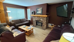 A living room with a stone fireplace, a sofa, a coffee table, and a television.