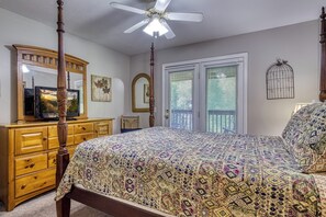 Quarto com cama de dossel, cômoda, televisão sobre a cômoda e ventilador de teto.
