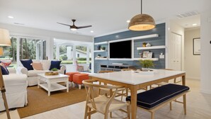 Un salon moderne avec un canapé blanc, une table basse et un coin repas comprenant une table et des chaises en bois.