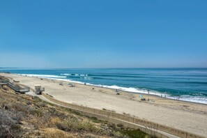 Ein Strand mit einer Betonpromenade, einem Rettungsturm und blauem Himmel.