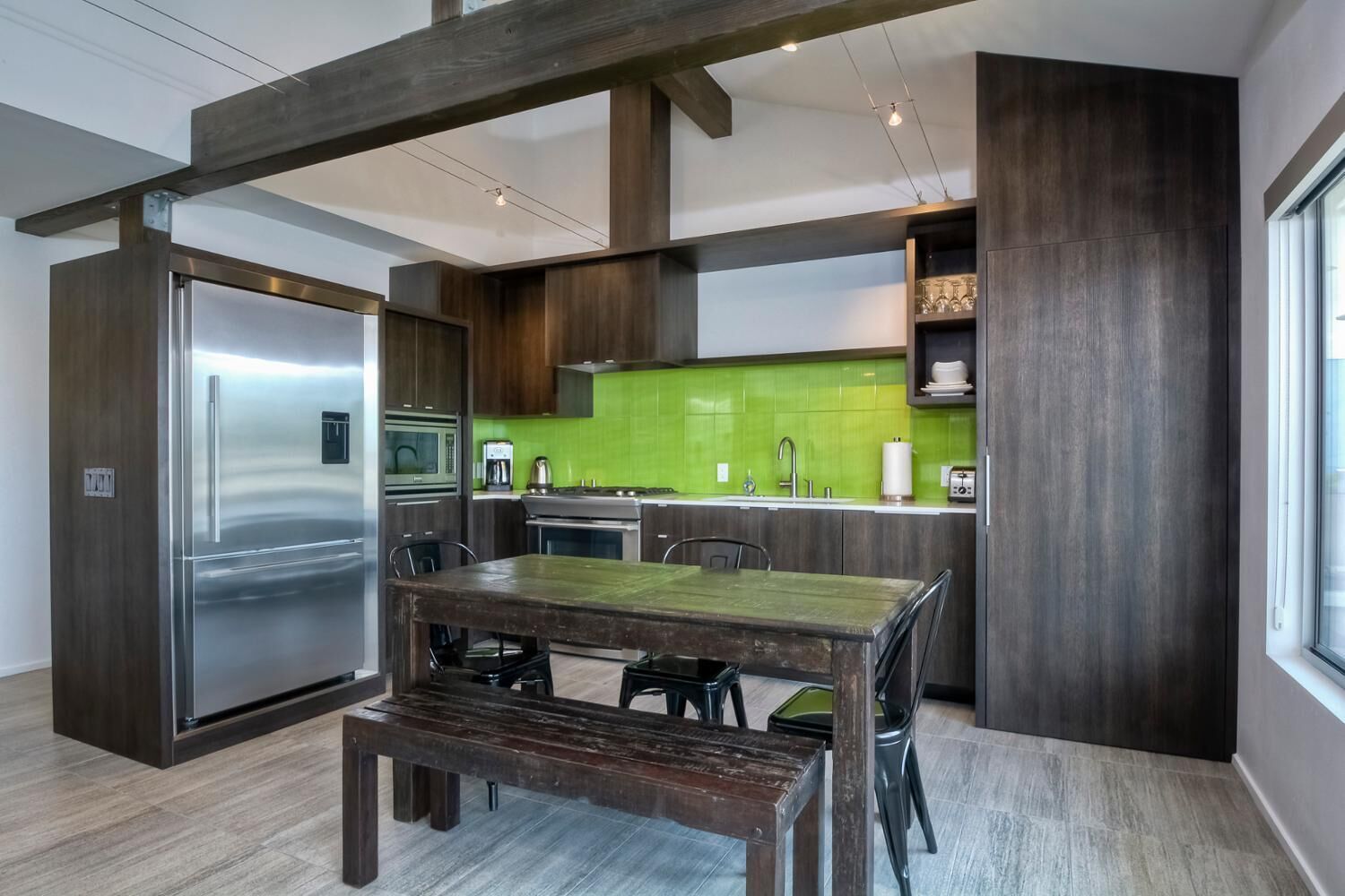 Una cucina moderna con frigorifero in acciaio inossidabile, zoccolo verde e mobili in legno.