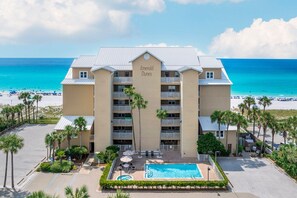 A hotel named 'Emerald Dunes' with a pool, surrounded by palm trees and a beach view.
