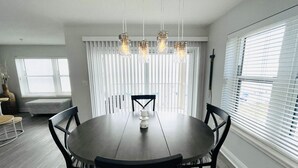 A dining area with a round table, black chairs, and pendant lights.