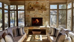 A cozy living room with a stone fireplace, large windows, and comfortable seating. - ALL 5 STAR REVIEWS! Walk to lake, dining & coffee. Private hot tub, assoc pool. (Union Pier)