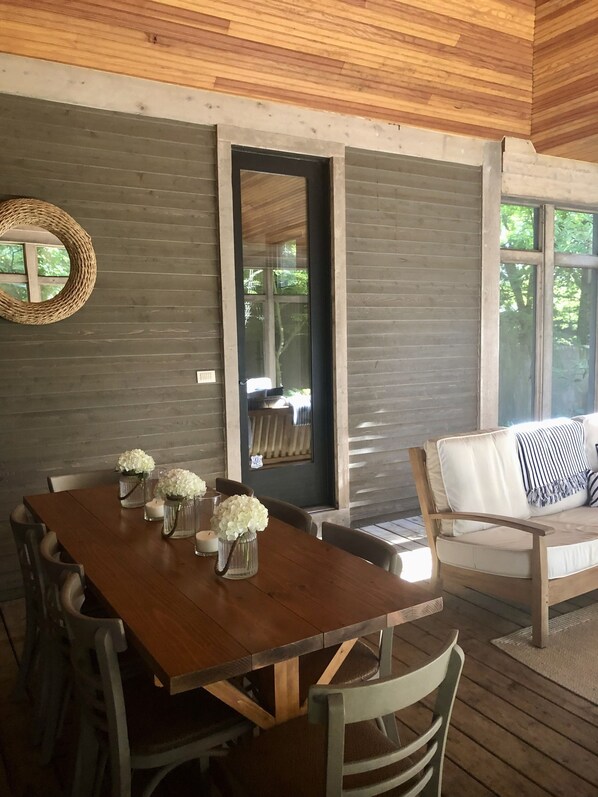 A wooden dining table with chairs, a sofa with a striped pillow, and a mirror on the wall. - ALL 5 STAR REVIEWS! Walk to lake, dining & coffee. Private hot tub, assoc pool. (Union Pier)