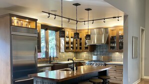 A modern kitchen with a central island, stainless steel appliances, and wooden cabinetry. - ALL 5 STAR REVIEWS! Walk to lake, dining & coffee. Private hot tub, assoc pool. (Union Pier)