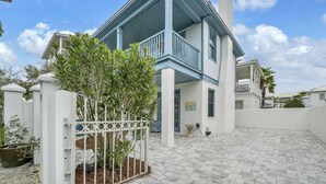 A two-story house with a balcony, a gated entrance, and a paved patio area. - Sunset Seeker-Gulf Side 30A Villa w/ Community Pool,Pet Friendly! (Seacrest Beach)