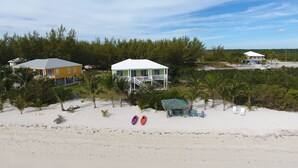 A beachside property with multiple houses, a sandy beach, and palm trees. - PRIVATE LUXURY Beachfront Home, Beach Cabana, Kayaks, Paddle Board (Casuarina Point)