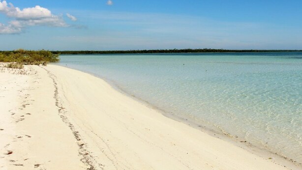 A beach with clear turquoise water and white sand.