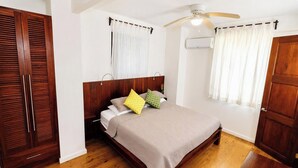 Un dormitorio con cama de madera, ventilador de techo y ventana con cortinas.