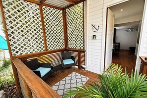 Un área de estar al aire libre techada con muebles de madera y un fondo de celosía.