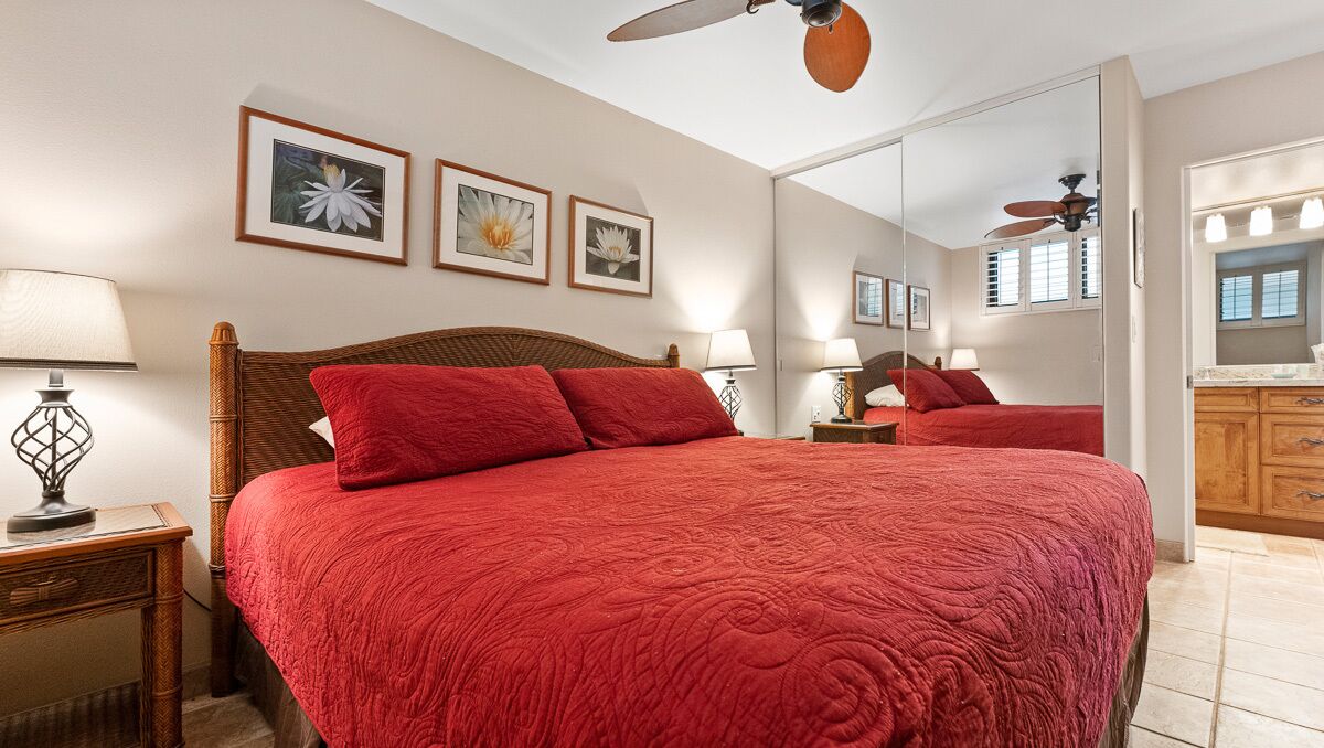 Ein Schlafzimmer mit einem großen Bett, einem Deckenventilator und einem Spiegel über dem Bett.