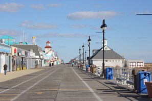 A boardwalk with shops, a lighthouse, and a beach in the background. - Amazing Location! PRIME location on Wesley. Includes Tags/Chairs/Umbrellas! (Ocean City)