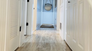 A hallway with wooden flooring, white doors, and a hanging mirror. - Amazing Location! PRIME location on Wesley.  Includes Tags/Chairs/Umbrellas!  (Ocean City)