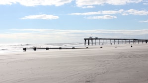 A beach with a pier extending into the ocean. - Amazing Location! PRIME location on Wesley.  Includes Tags/Chairs/Umbrellas!  (Ocean City)