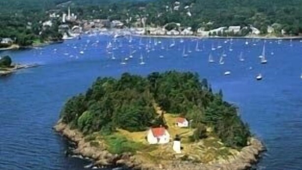 Escena costera con una pequeña isla que presenta un edificio de techo rojo rodeado de vegetación.