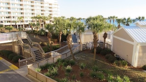 A hotel courtyard with palm trees, a pool, and a building with balconies. - Panama City Beachfront! 5STAR Dog Friendly! Vacation-Staycation or MicroCation! (Panama City Beach)