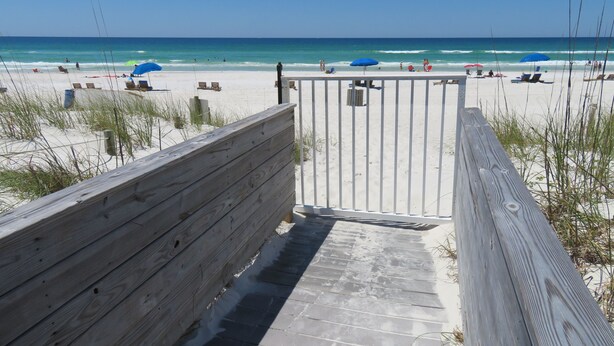 A wooden boardwalk leading to a beach with umbrellas and beach chairs. - Panama City Beachfront! 5STAR Dog Friendly! Vacation-Staycation or MicroCation! (Panama City Beach)