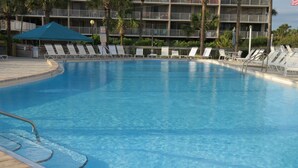 A swimming pool with lounge chairs and a building in the background. - Panama City Beachfront! 5STAR Dog Friendly! Vacation-Staycation or MicroCation! (Panama City Beach)