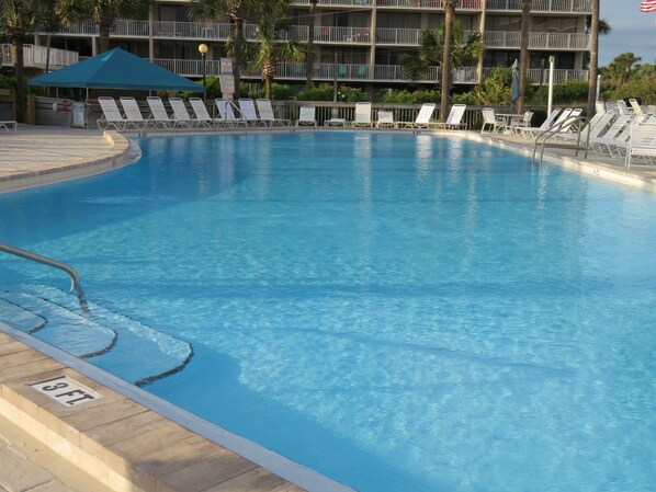A swimming pool with lounge chairs and a building in the background.
