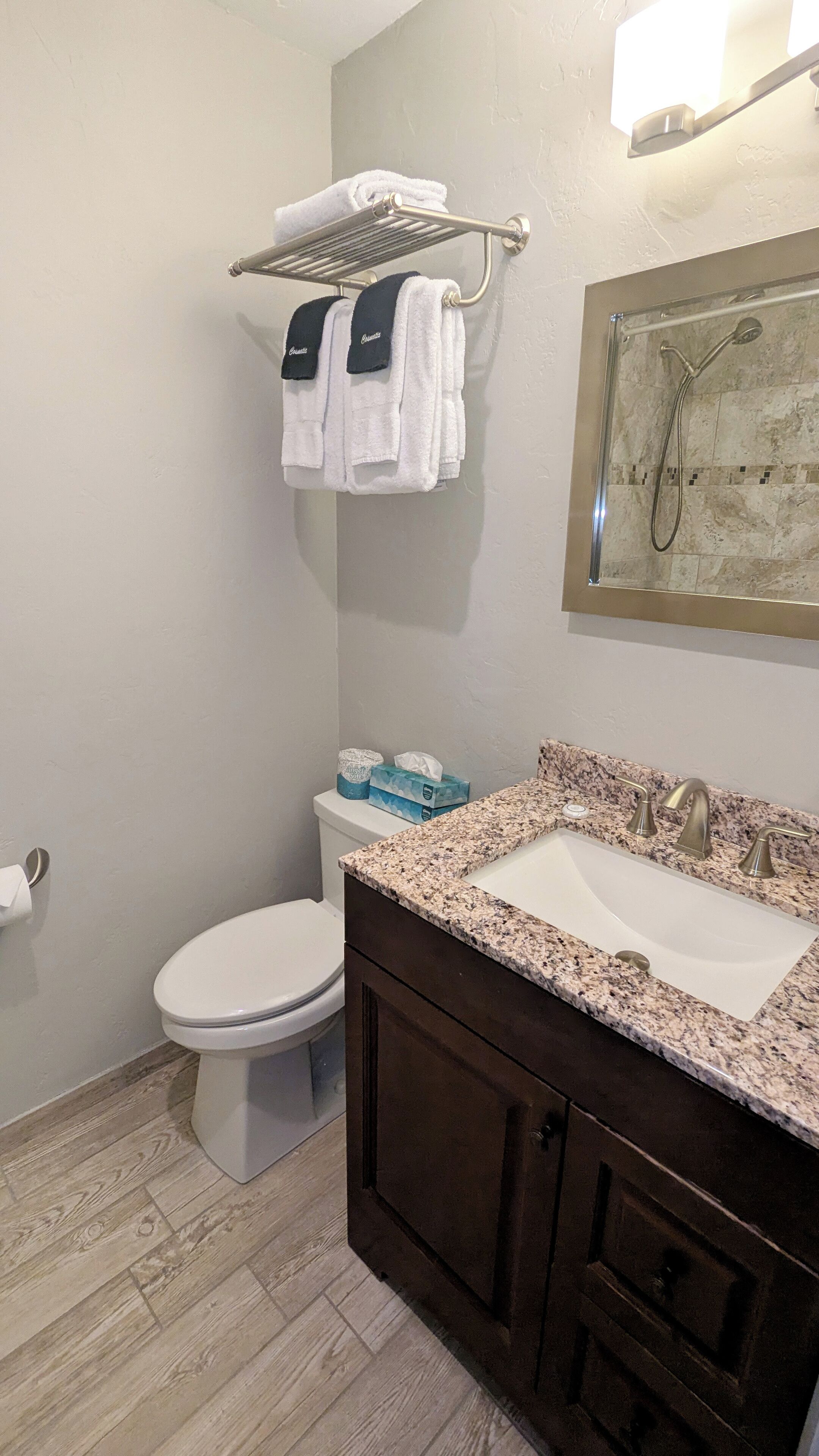 A bathroom with a toilet, sink, shower, and towel rack.
