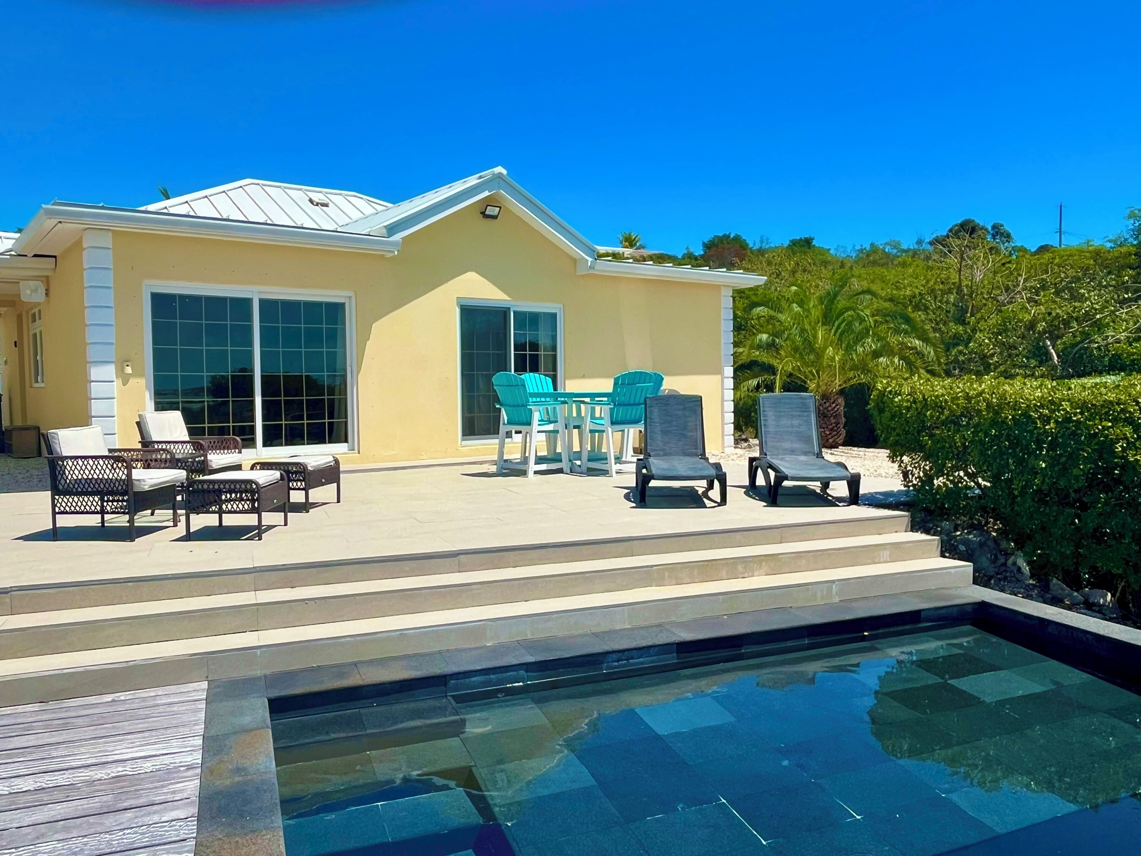 Une maison avec une piscine, du mobilier d’extérieur et de grandes fenêtres.