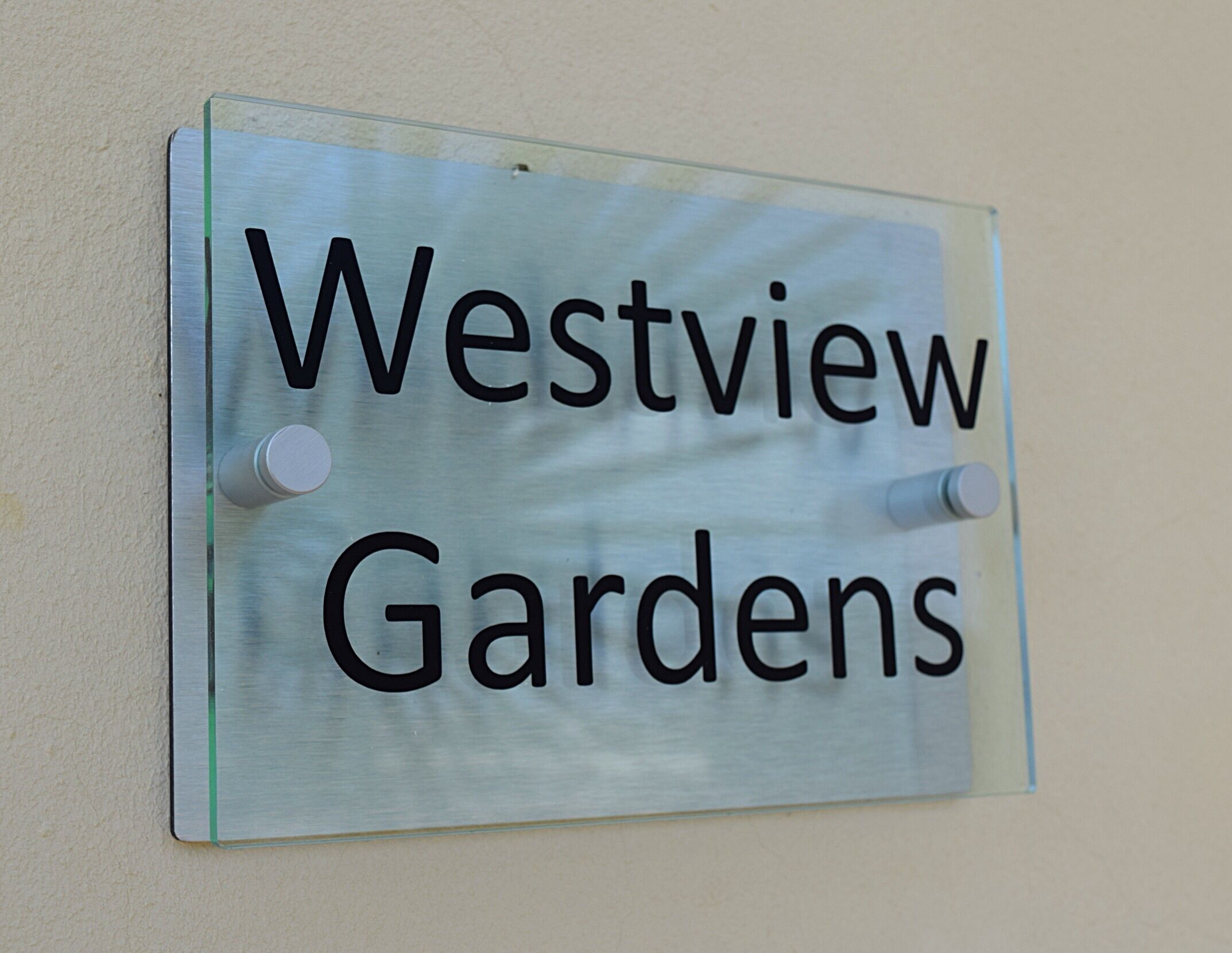 En skylt med texten ”Westview Gardens” som är monterad på en vägg.