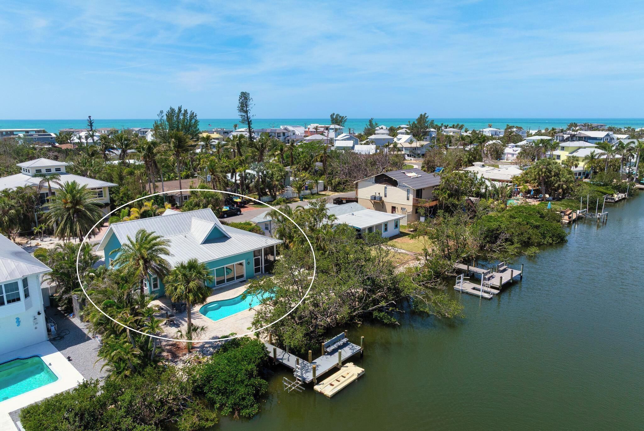 A coastal residential area with houses, a swimming pool, and a dock.
