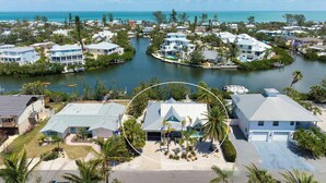 A coastal residential area with houses surrounded by water, featuring a central house with a garage and a swimming pool. - Perfect Anna Maria. Dock on Canal - 3 blocks to sugar sand beach. Heated pool. (Anna Maria)