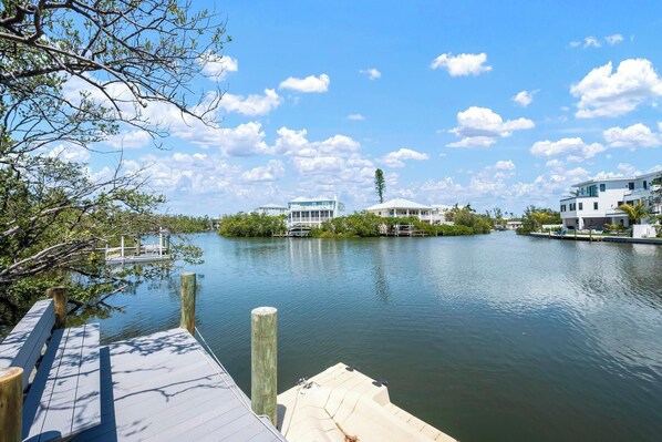 A waterfront property with a dock, a boat, and several modern houses with large windows and balconies.