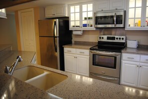 Enjoy cooking in this well-equipped kitchen with a double sink, refrigerator, microwave, and oven.