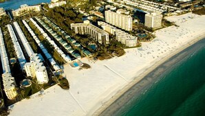 Ett flygbildsfoto av en kustort med flera höga hotell, en sandstrand och ett klart, blått hav.
