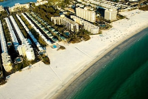 Vista aerea di una località balneare con diversi alberghi alti, una spiaggia sabbiosa e un oceano blu cristallino.