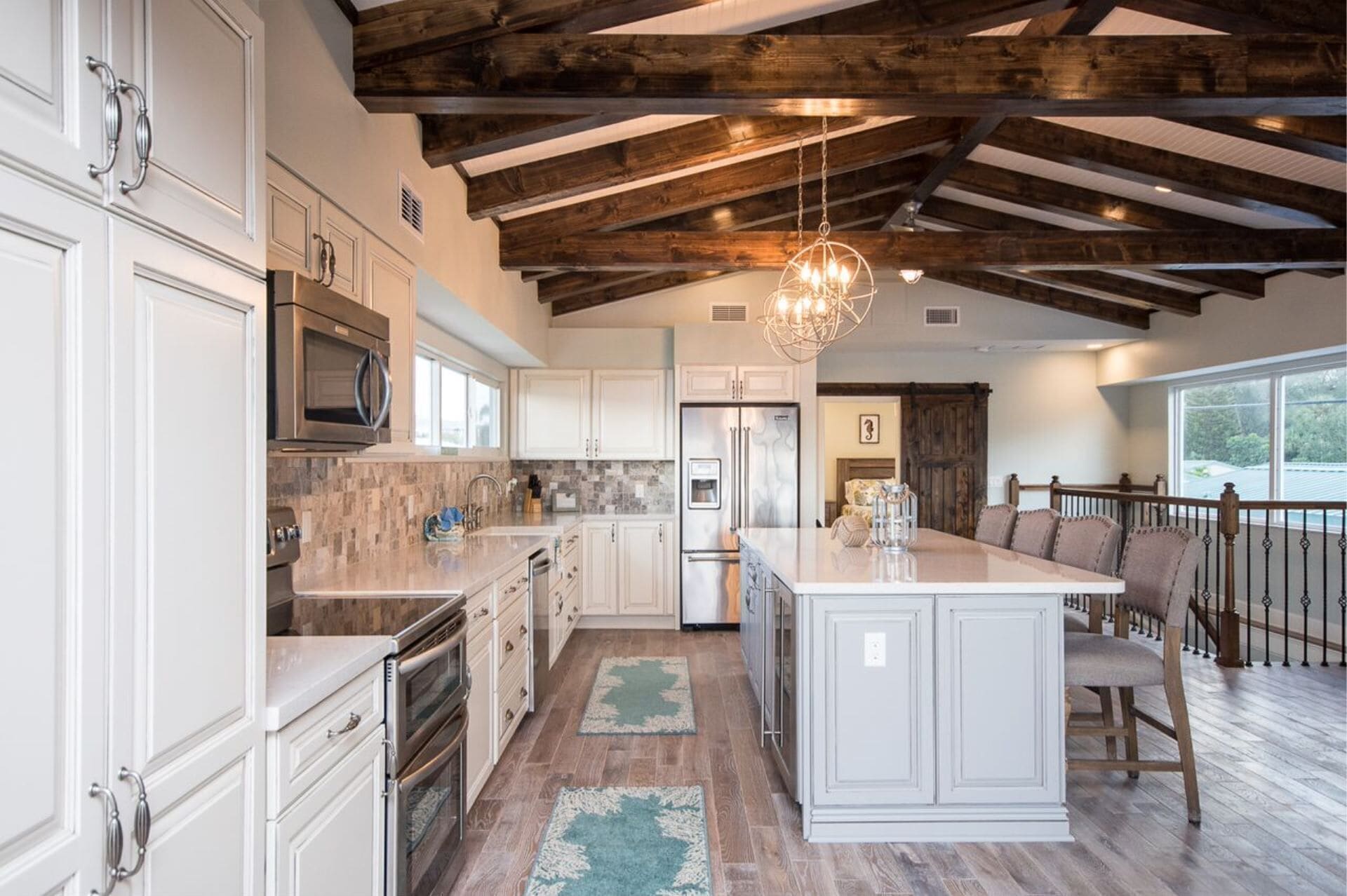 A spacious kitchen with white cabinetry, a central island, and a wooden ceiling.