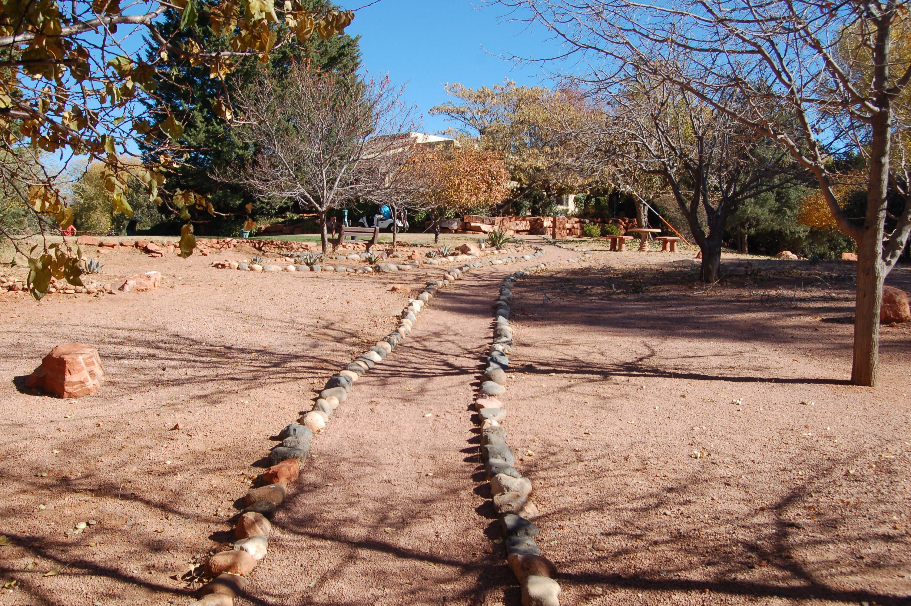 A park with a stone pathway, benches, and trees.