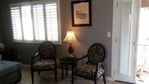 A living room with two zebra-patterned chairs, a small table with a lamp, a framed picture on the wall, and a sliding glass door leading outside. - North Central Phoenix - Two Master Stes. 1500 Sf Newly Remodeled, Peaceful!! (Phoenix)