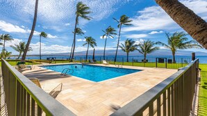 Une piscine avec vue sur l’océan, entourée de palmiers et sous un ciel dégagé.