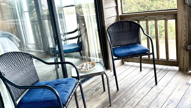 Une terrasse en bois avec deux fauteuils en osier et une petite table.