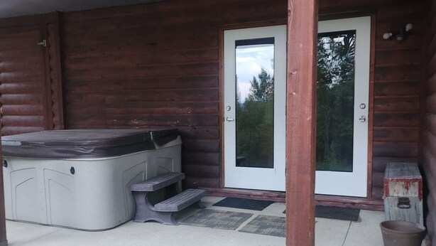 Une cabane en bois avec un jacuzzi et une porte dotée d’un panneau de verre.