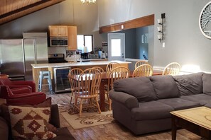 A modern kitchen with stainless steel appliances, wooden cabinets, and a dining area with a wooden table and chairs. - Spacious 11BR Cabin Near Granby Ranch + Free Belize Week (Granby)