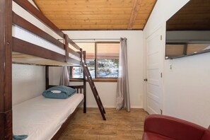 A bunk bed room with a window, a red chair, and a door. - Spacious 11BR Cabin for Groups | Near Granby Ranch (Granby)