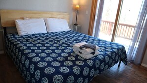 Une chambre à coucher avec une tête de lit en bois, une couvre-lit à motifs, une table de chevet avec une lampe et une vue par la fenêtre.