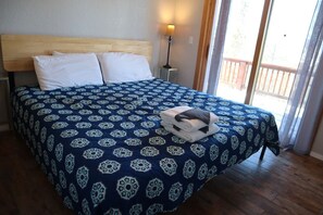 A bedroom with a wooden headboard, a patterned bedspread, a nightstand with a lamp, and a view through a window. - Spacious 11BR Cabin for Groups | Near Granby Ranch (Granby)