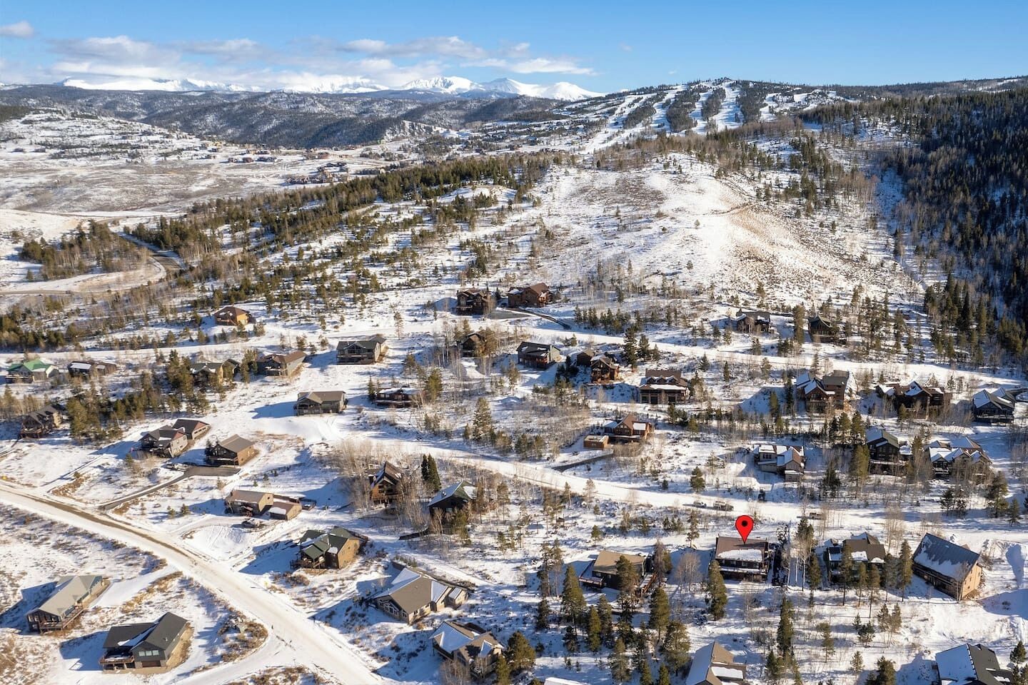 Une ville de montagne enneigée, avec de nombreux bâtiments, des routes et une piste de ski.