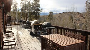 A wooden deck with outdoor furniture, a barbecue grill, and a propane tank.