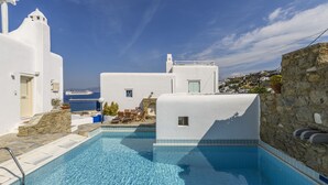 A swimming pool with stone tiles, white buildings, and a view of the sea. - Mykonos Perla Town House - Perfect Location with Pool and Private Parking - 2 BR (Mykonos)